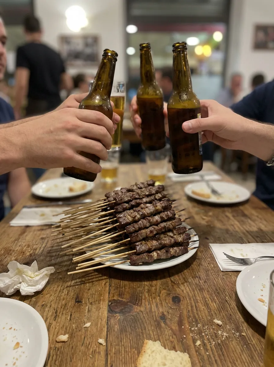 Amici che brindano con birre sopra un piatto di arrosticini da Rostelle and Co.